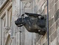 Photo d'une gargouille très sale et accrochée sur une façade de bâtiment.