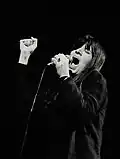 Une femme en noir et blanc chante en serrant le poing.