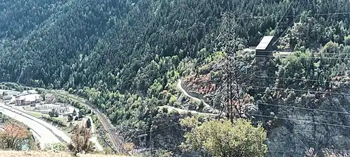 Photographie d'une usine électrique et gare de départ du téléphérique, dominant plus ou moins une vaste forêt.