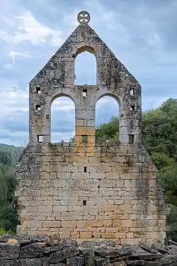 Façade d'un bâtiment ruiné conservant à son sommet l'insigne des Templiers.