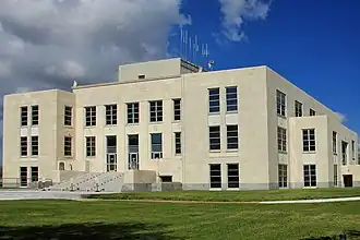 Vue d'un grand bâtiment blanc de trois étage, avec de la pelouse au premier-plan