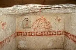 Vue d'une pièce souterraine munie de fresques peintes en rouge