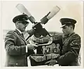 A gauche, Nathan Landman, rabbin aumônier de l'Armée de l'air pour la France, l'Espagne et la Libye, examine le shofar et d'autres équipements religieux du grand jour avant de décoller de la base aérienne d'Evreux-Fauville (France) pour Tripoli (Libye), lors de la première étape d'un circuit de 3&nbsp;000 milles dans lequel il effectue huit services sur cinq bases avant de revenir à Evreux pour Yom Kippour. À droite, le spécialiste des services d'aumônerie juive, David Cohen d'Everett (Massachusetts), septembre 1964