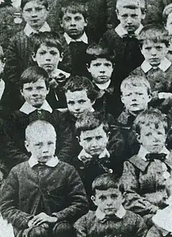 Photo en noir et blanc de plusieurs enfants en uniformes regardant l'objectif.