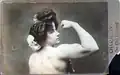 Carte postale promotionnelle montrant Charmion de trois-quart dos, le dos dénudé et le bras droit plié pour mettre en valeur son épaule et son biceps ; elle regarde vers l'objectif et le spectateur