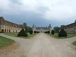 L’allée bordée de buis encadrée par les communs.