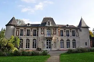Un château flanqué à gauche d'une tour ronde coiffée d'une poivrière. Le corps de bâtiment principal est en pierre jaune avec des incrustations de briques rouges. La porte d'entrée centrale est surmontée d'un balcon orné et d'une lucarne. La tour de droite est une tour carrée.