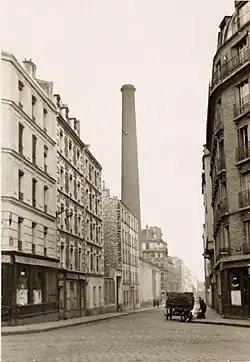Ancienne photo avec une cheminée en briques de la raffinerie Say.