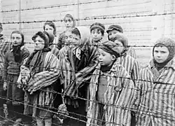 Photographie d'enfants en haillons derrière des barbelés