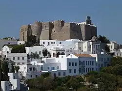 Photographie d'un monastère fortifié surplombant un village.