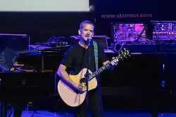 Photo d'un homme sur scène jouant de la guitare acoustique