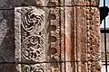 Détail de la porte centrale de la façade sud. Rinceaux (à gauche) et bande torsadée (à droite).