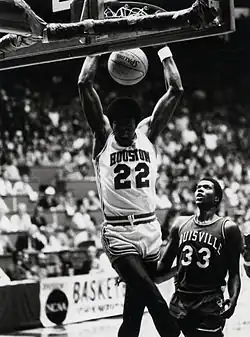 Clyde Drexler dunkant à deux mains, sous les yeux d'un adversaire.