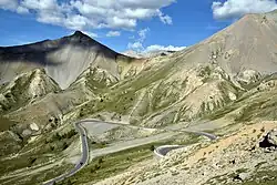 Photo montrant plusieurs lacets de la route avec en arrière plan des montagnes presque dépourvues de végétation.