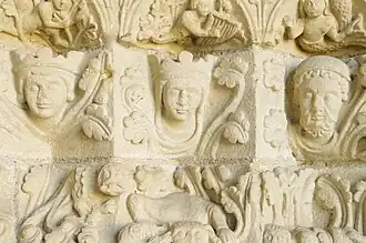 Photographie en couleurs de bas-reliefs représentant des figures humaines encadrées de motifs végétaux.