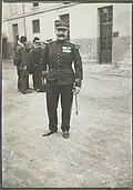 Photographie en noir et blanc d'un homme, de pied, en tenu militaire, portant le képi.