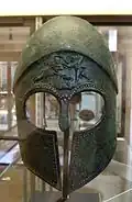 Casque corinthien (Cabinet des Médailles, Paris, BnF). Bronze, petits clous d'argent, début du Ve siècle av. J.-C. ; le front porte une représentation en relief de la dispute d'Héraclès et d'Apollon pour la biche de Cérynie. Fabriqué à Vulci.