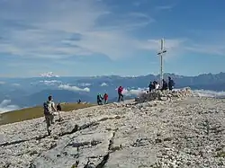 Randonneurs se pressant autour d'une grande croix et profitant d'un large panorama.