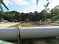 photo du bassin extérieur d’une piscine, l’eau est marron et les lignes d’eau ne sont plus droites