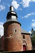 L'entrée de l'église est protégée par une imposante tour percée de meurtrières et surmonté d'un clocher d'inspiration flamande.