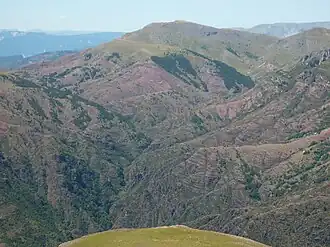 Vue du dôme de Barrot avec sa masse de 900&nbsp;m d'épaisseur de pélites rouges du Permien entamées ici par le ruisseau de Raton, affluent de rive ouest du Cians.