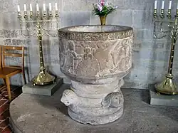 Baptistère médiéval en pierre sculptée, ambiance solennelle.