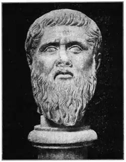 Tête sculptée en pierre blanche d'un homme barbu levant les yeux au ciel d'un air tourmenté.
