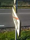 Panneau de sortie de Passins de la RD 517, de profil. Noter l’effet « ombre » des lettres sur le panneau.