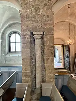 Intérieur ancien centré sur une colonne en pierre, éclairé naturellement, ambiance paisible.