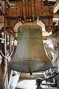 Grande cloche suspendue dans un clocher, détails visibles, ambiance solennelle.