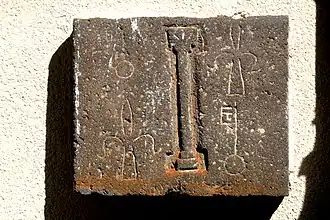 Dalle en pierre de Volvic comportant au centre une colonne avec chapiteau, entourée des armes de l'abbaye de manière alternée.