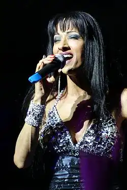 Femme aux cheveux bruns fermant les yeux et chantant dans un microphone