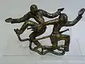 Boucle en bronze doré aux deux figures dansantes. Tombe no&nbsp;13 Shizhaishan, Jinning. Royaume Dian. Musée provincial du Yúnnán, Kunming.