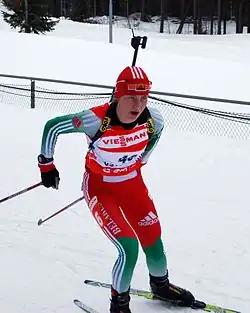 Biathlète féminine en train de skier, son fusil dans le dos.