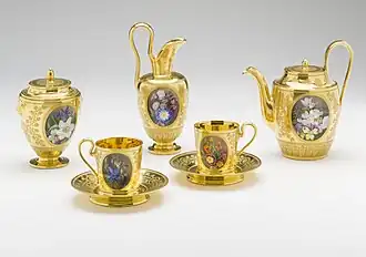 Un service à thé doré, orné de petites peintures ovales.