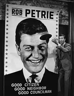 Photo d'un homme jetant son chapeau devant une affiche d'élection.