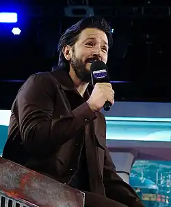 Homme aux cheveux bruns tenant un microphone.
