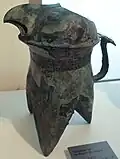 Verseuse à alcool he en forme de rapace. Bronze. Dynastie Shang. Début de la phase d’Anyang, XIIIe&nbsp;– XIIe&nbsp;siècle&nbsp;av. J.-C. . H. 23, 8&nbsp;cm. Musée Guimet