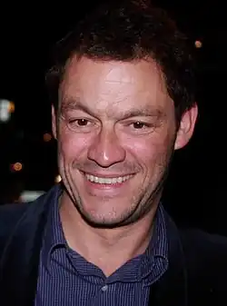 Photo d'un homme vu de face en train de sourire cadré en gros plan.