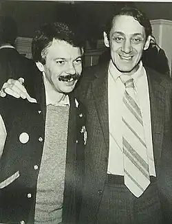 Photographie en noir et blanc de Milk avec le bras sur l'épaule d'un autre homme.