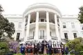 Donald Trump faisant un discours devant l'équipe des Patriots en costumes et la Maison Blanche.