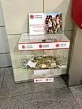 Boîte de dons de Caritas Kosovo à l'aéroport international de Pristina.