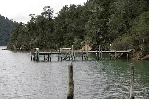 Ponton en bois le long d'une côte boisée et pentue.