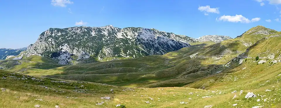 Hauts plateaux recouverts d'herbe, sans constructions humaines, à part une route qui serpente à flanc de relief.