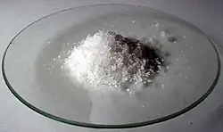 Poudre grossière blanche dans un verre de montre.
