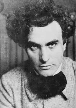 Photographie en noir et blanc d'un jeune homme brun au regard noir, de face.