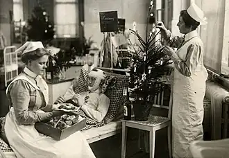 Infirmières, gâteaux et sapin de Noël autour d'un blessé pour le premier Noël de guerre, décembre 1914.