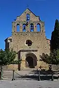 Façade avec son clocher peigne du XIVe&nbsp;siècle. Le portail est surmontée d'une haute muraille réalisée après la guerre des Albigeois.