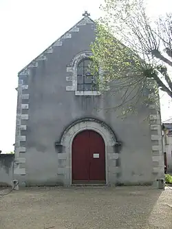 Photographie en couleurs de la façade d'un édifice religieux percée d'une porte surmontée d'une baie.