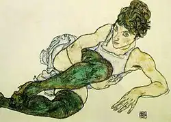 Portrait d'une femme allongée sur son coude gauche, jambes en bas verts repliées sur la poitrine, bras droit sous un genou